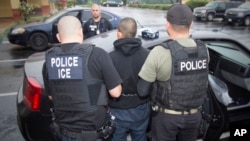 FILE - photo released by U.S. Immigration and Customs Enforcement shows foreign nationals being arrested this week during a targeted enforcement operation conducted by U.S. Immigration and Customs Enforcement (ICE).