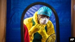 FILE - A health care worker dons protective gear before entering an Ebola treatment center in Freetown, Sierra Leone.