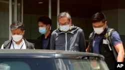 File - Police officers escort Cheung Kim-hung, CEO and Executive Director of Next Digital Ltd at Apple Daily headquarters in Hong Kong, June 17, 2021.