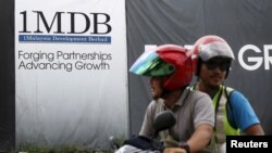 FILE - Motorcyclists pass a 1Malaysia Development Berhad (1MDB) billboard at the Tun Razak Exchange development in Kuala Lumpur, Malaysia, Feb. 3, 2016