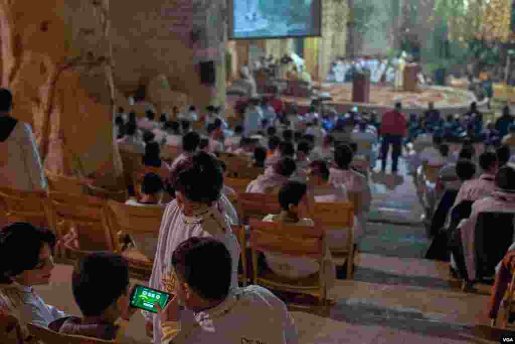 Some 21st century pastimes clash with ancient traditions as young worshipers play a video game during Christmas Mass. (Hamada Elrasam/VOA)
