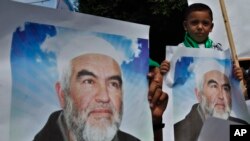 FILE - Palestinians in Gaza City carry pictures of Sheikh Raed Salah, leader of the Islamic Movement in Israel, during a protest to condemn what protesters claim was a desecration of Al-Aqsa Mosque in Jerusalem by Jewish extremists, Sept. 4, 2013. 