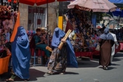 FILE - Burqa-clad women shop at a market in Kabul, Aghanistan, Aug. 23, 2021, following the Taliban's takeover of the country.
