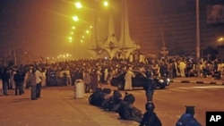 Security forces watch demonstrators protesting the elimination of a popular fuel subsidy that caused the price of petrol to double overnight gather at the Silver Jubilee roundabout in the restive central Nigerian city of Kano, January 4, 2012.