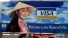 FILE - Tourists walk past advertisements of foreign companies near the airport of Ho Chi Minh City (formerly Saigon) March 8, 1994.