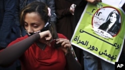 Seorang perempuan Mesir memotong rambutnya sebagai protes atas konstitusi yang berhaluan Islam di Tahrir Square, Kairo (25/12). Poster berbahasa Arab itu berbunyi 'Jangan Pinggirkan Peran Perempuan'. 