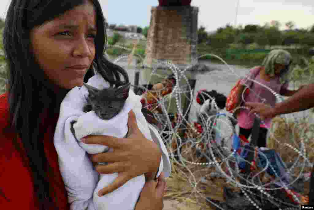 A migrant from Venezuela holds her cat named "Grey" that she picked up along the route, after crossing the Rio Grande and making her way through the razor wire into the United States in Eagle Pass, Texas, Sept. 26, 2023.