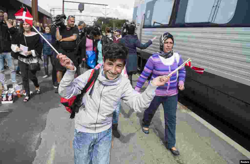 A boy waves Danish flags as he joins fellow migrants, mainly from Syria, on Padborg station to board a train heading to Sweden. Many refugees are moving across Denmark from Germany to reach Sweden, which has one of Europe's most open policies toward asylum seekers.