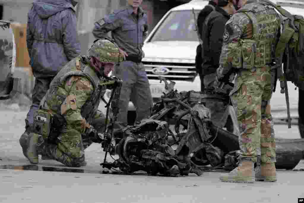 U.S. forces examine the remains of a car after a suicide car bomb attack on the Jalalabad-Kabul road in Kabul, Afghanistan, Dec. 27, 2013.