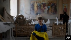 A boy helps salvage items at the Odesa Transfiguration Cathedral after it was heavily damaged in Russian missile attacks in Odesa, on July 23, 2023. (Jae C. Hong/AP)