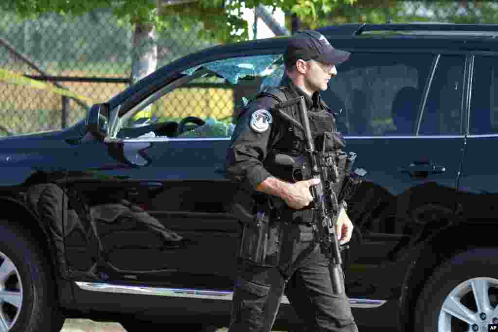A Capitol Hill Police officer walks past an automobile with the driver's window damaged at the scene of a shooting in Alexandria, Virginia, where House Majority Whip Steve Scalise was shot, June 14, 2017.