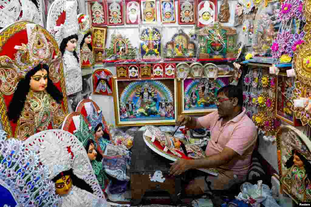 An artisan paints a decorative Hindu goddess Durga piece inside a shop ahead of the Durga Puja festival in Kolkata, India.