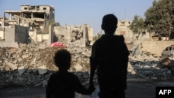 Anak-anak memandang ke arah bangunan yang hancur akibat serangan udara Israel di kamp pengungsi Nuseirat di pusat Jalur Gaza, Kamis, 7 November 2024. (Foto: Eyad Baba/AFP)