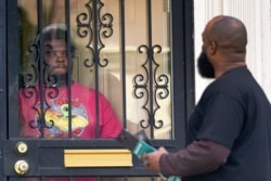 FILE - Anthony Brinson, right, talks with a resident while leaving a flyer at a home in Detroit, May 4, 2021. Officials are walking door-to-door to encourage residents of the majority Black city to get vaccinated against COVID-19.