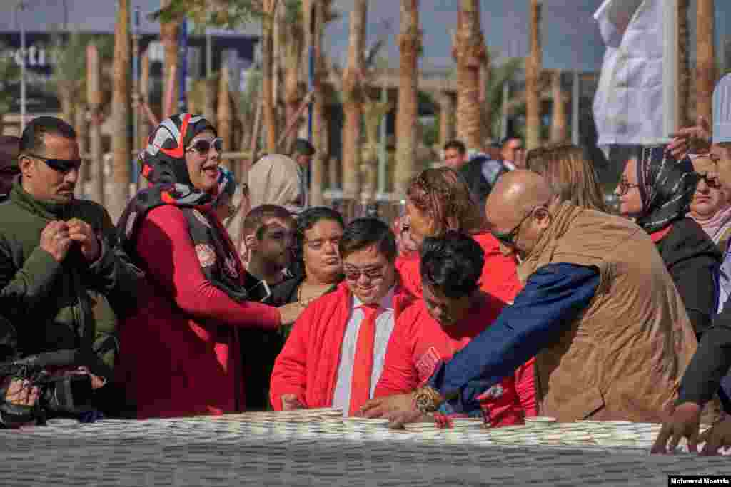 Some Egyptian children and teenagers with Down syndrome helped finish the last line of cups for King Tut's mask. (H. Elrasam/VOA)