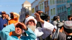 Orang-orang memandangi mayat yang digantung oleh Taliban dari derek di alun-alun utama kota Herat di Afghanistan barat, 25 September 2021. (Foto: AP)