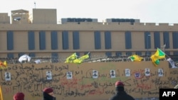 Foto-foto kombatan Kataeb Hizbullah terpasang di dinding gedung Kedutaan Besar AS di Baghdad, Ibu Kota Irak, 1 Januari 2020. (Foto: AFP)