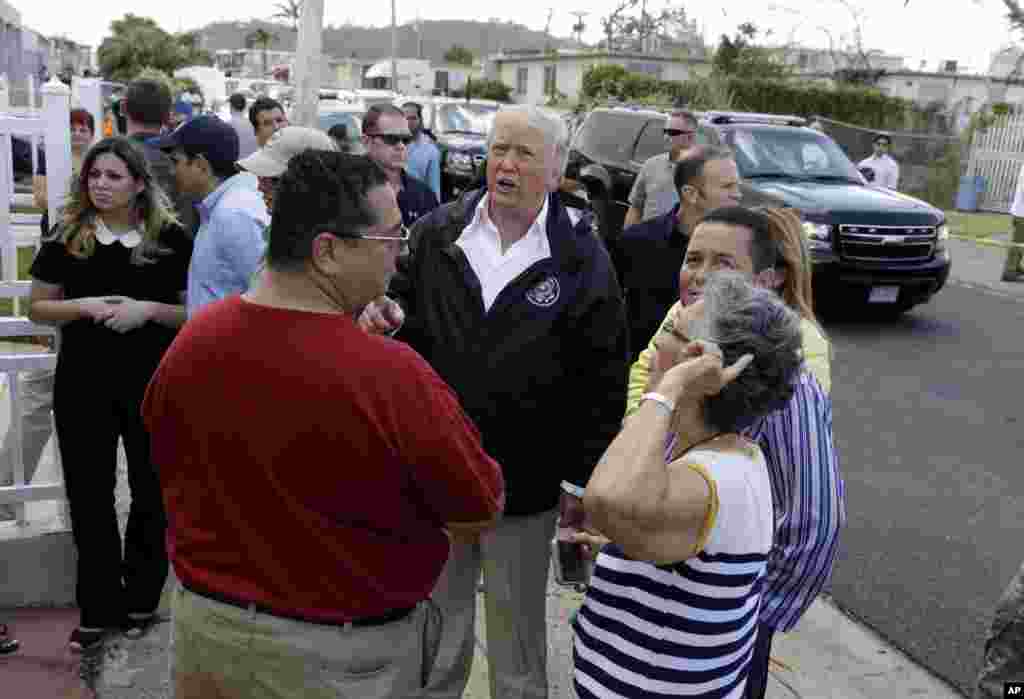 President Donald Trump talks to residents while taking a walking tour to survey hurricane damage and recovery efforts in a neighborhood in Guaynabo, Puerto Rico, Oct. 3, 2017.