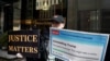 Una mujer sostiene pancartas frente a la Trump Tower neoyorquina, días después de que el expresidente de EEUU, Donald Trump, afirmara que esperaba ser arrestado y pedía a sus seguidores que protestaran en Nueva York, el 22 de marzo de 2023
