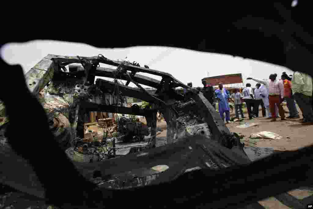 People inspect the remains of a car bomb in Jos, Nigeria, May 21, 2014.