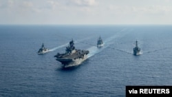Kapal pengawal milik angatan laut Australia yang dilengkapi dengan peluru kendali HMAS Parramatta (FFH 154) (kiri) berlayar bersama kapal perang milik angkatan laut AS dalam sebuah patroli di laut China Selatan pada 18 April 2020. (Foto: U.S. Navy via Reuters)