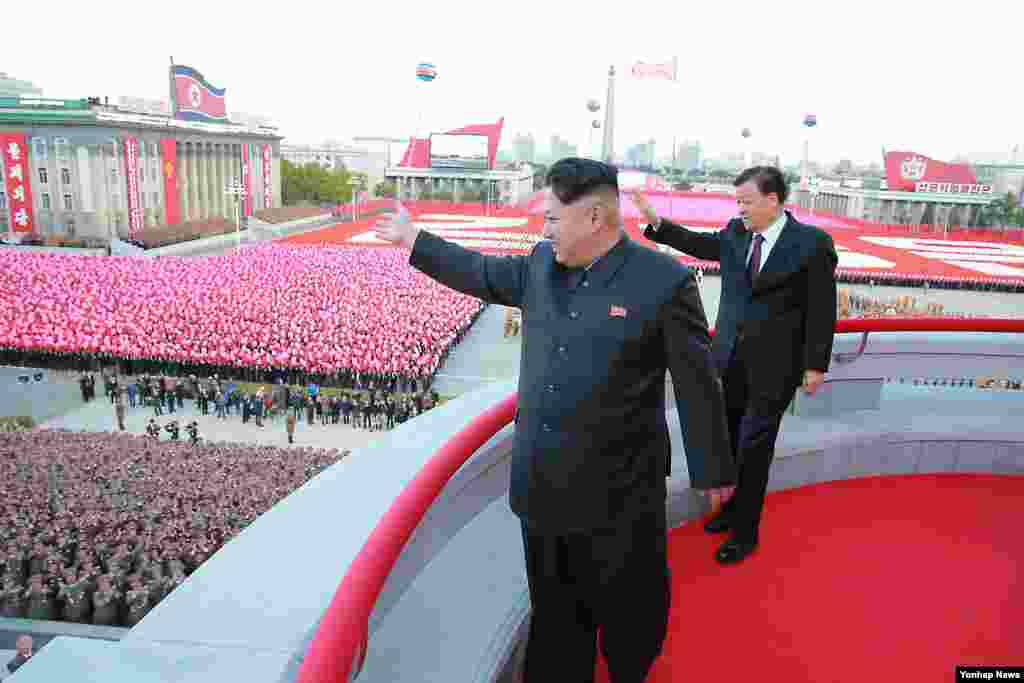朝鲜领导人金正恩同中共政治局常委同刘云山在平壤的朝鲜"劳动党"建党70周年阅兵式上招手(2015年10月10日)。