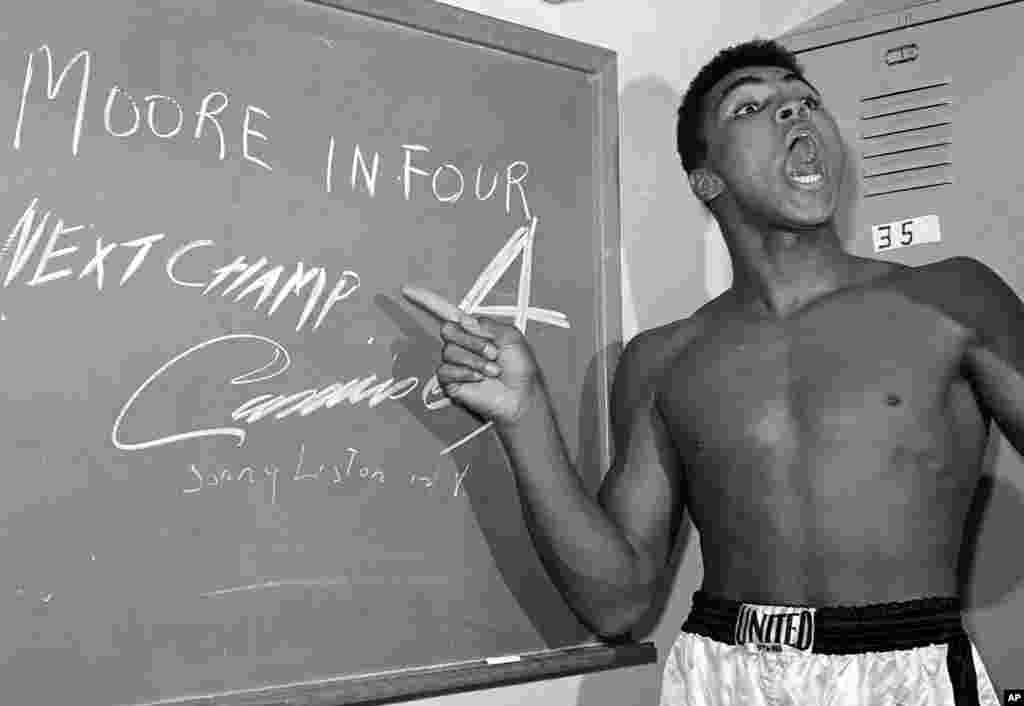 Dalam foto tertanggal 15 November 1962, Muhammad Ali, saat masih bernama Cassius Clay, menunjuk tulisannya di papan tulis yang menyatakan prediksinya mengalahkan Archie Moore dalam empat ronde, dan itu terjadi. (AP/Harold P. Matosian)