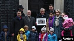 Labour peer Alf Dubs (C) poses with protestors as he delivers a petition to Number 10 Downing Street opposing the closure of a government scheme to bring unaccompanied child refugees to Britain from Europe, in London, Feb. 11, 2017. 
