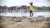 A woman wades near a beach in Monrovia, Liberia. Though poverty does not discriminate, women have fewer resources to cope. 