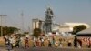 FILE - Members of the mining community carry donated food parcels at the Khomanani mine in Rustenburg, South Africa, May 2014. 