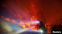 Angin meniupkan bara api dari pepohonan yang terbakar saat petugas pemadam kebakaran berusaha memadamkan api di Malibu, California, pada 10 Desember 2024. (Foto: Reuters/Ringo Chiu)