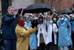 Mayor Bill de Blasio and his wife Chirlane McCray applaud healthcare workers at Brooklyn's Kings County Hospital Center during a 7 o'clock ceremony, April 24, 2020, in New York.