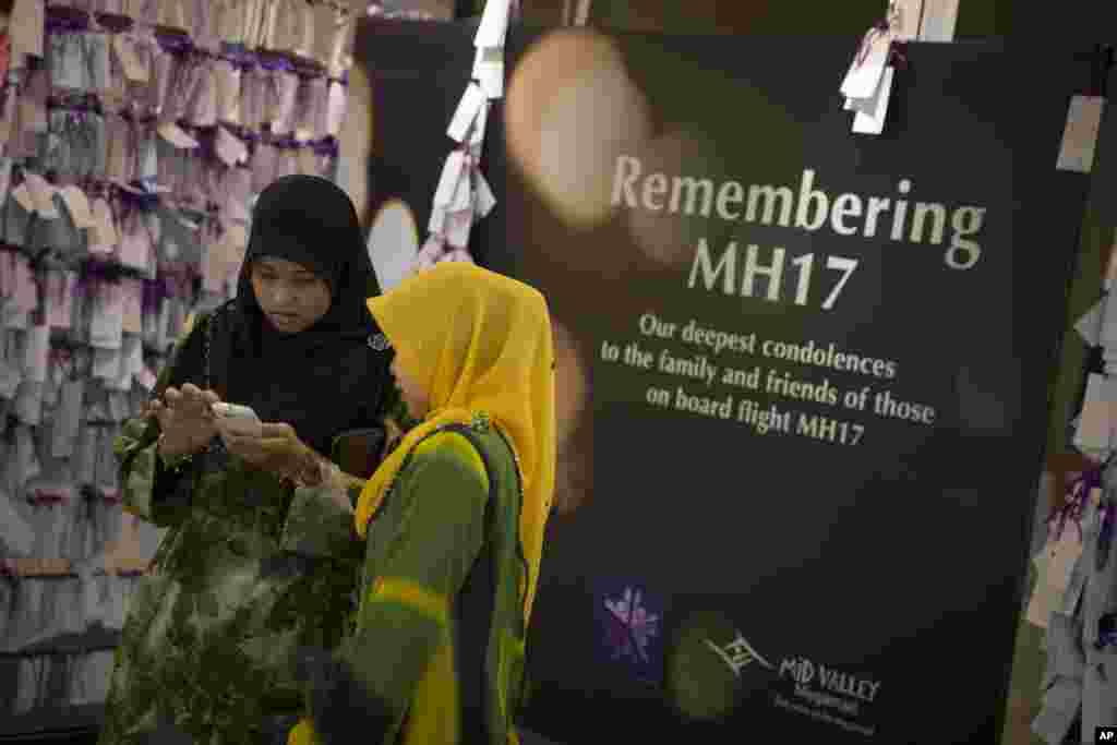 Shoppers take photos next to prayer notes for passengers aboard Malaysia Airlines Flight MH17 at a shopping mall in Kuala Lumpur, July 24, 2014.