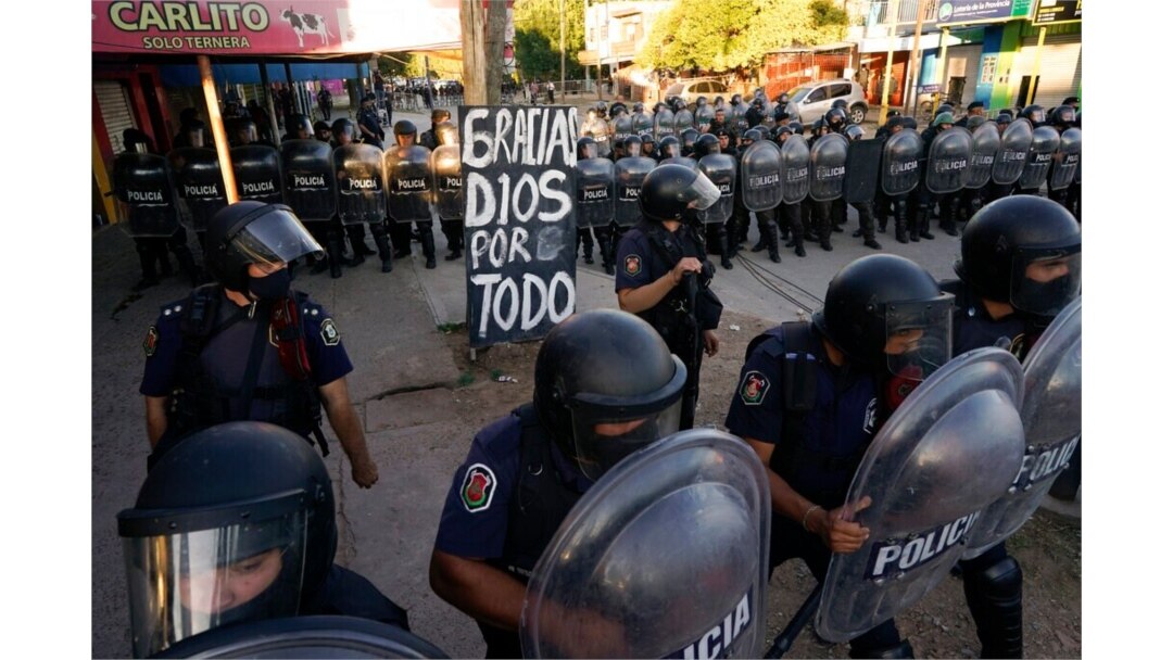 A sign set up by mourning fans reads in Spanish, "Thank You God for Everything," as police block their access to the Jardin de Bellavista cemetery during the burial of Diego Maradona in Buenos Aires, Argentina, Nov. 26, 2020.