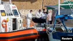 Petugas layanan darurat membawa jenazah korban kapal migran yang terbakar di lepas pantai Crotone, ke dermaga Le Castella , Italia, 30 Agustus 2020.