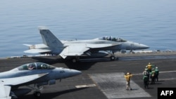 2014年8月8日美国海军水兵在乔治布什航空母舰上指挥执行任务的超级大黄蜂式打击战斗机