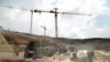 FILE - Workers and buldozers working at a construction site in the Israeli settlement of Givat Zeev near the West Bank city of Ramallah, April 14, 2016.