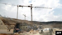 FILE - Workers and buldozers working at a construction site in the Israeli settlement of Givat Zeev near the West Bank city of Ramallah, April 14, 2016.