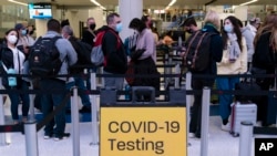 Pelancong mengantre untuk pemeriksaan di dekat tanda tempat pengujian COVID-19 di Bandara Internasional Los Angeles di Los Angeles pada 24 November 2021. (Foto: AP)