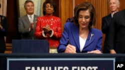 House Speaker Nancy Pelosi of Calif. accompanied by other legislators, signs the Coronavirus Aid, Relief, and Economic Security (CARES) Act. after it passed in the House on Capitol Hill, March 27, 2020, in Washington. 