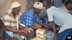 Seorang pelanggan Dahabshiil, sebuah tempat penukaran uang di Somalia, menukarkan lebaran uang dolar dengan mata uang Somalia di Mogadishu, Somalia (Foto: dok).