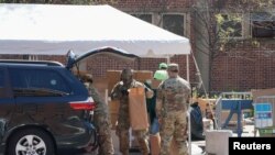 疫情期間，美國陸軍國民警衛隊員在紐約市曼哈頓哈萊姆區向民眾分發由多家市政府機構提供的免費食物。(2020年4月15日)