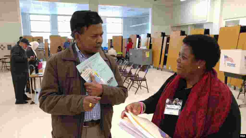 Virginia voter gets election materials from polling station worker before voting in US presidential election, Nov. 8, 2016. (Photo: D. Block / VOA)