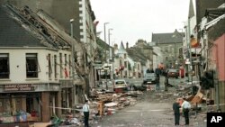 FILE - Royal Ulster Constabulary Police officers stand on Market Street, the scene of a car bombing in the centre of Omagh, Co Tyrone, 72 miles west of Belfast, Northern Ireland, on Aug. 15, 1998. It has been 25 years since the striking of the Good Friday Agreement, the landmark peace accord that ended three decades of violence in Northern Ireland, a period known as “the Troubles.”
