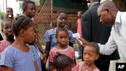In this Monday, Jan. 19, 2015 file photo, a health care worker, right, takes the temperatures of school children for signs of the Ebola virus before they enter their school in the city of Conakry, Guinea. The World Health Organization says it will soon start large-scale testing of an experimental Ebola vaccine in Guinea to see how effective it might be in preventing future outbreaks of the dreaded virus. In a statement issued on Thursday, March 5, 2015, the U.N. health agency said the study will be focused in Basse Guinee, the region that currently has the most Ebola cases in the country. (AP Photo/Youssouf Bah, File)