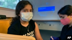Maya Huber (kiri) turut serta dalam uji coba pemberian vaksin COVID-19 Pfizer untuk anak-anak di Universitas Rutgers di New Brunswick, New Jersey, pada 14 Juni 2021. (Foto: Nisha Gandhi via AP)