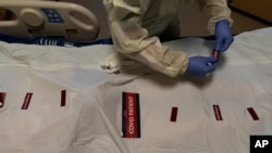 FILE - Registered nurse Bryan Hofilena attaches "COVID Patient" stickers on a body bag of a patient who died of coronavirus at Providence Holy Cross Medical Center in Los Angeles, Dec. 14, 2021.