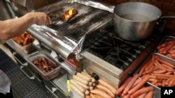 FILE - A cook at Hot Doug's cooks orders for customers at the gourmet hot dog diner in Chicago, May 7, 2014. 