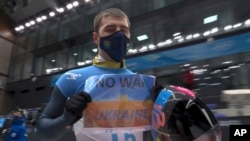 In this frame grab from video, Vladyslav Heraskevych, of Ukraine, holds a sign that reads "No War in Ukraine" after his run at the men's skeleton competition at the 2022 Winter Olympics, in the Yanqing district of Beijing, China, Feb. 11, 2022. (NBC via AP)
