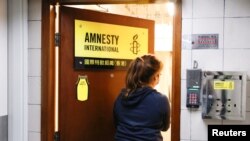 Seorang perempuan memasuki kantor Amnesty International Hong Kong, setelah pengumuman akan menutup kantor tersebut karena undang-undang keamanan nasional yang diberlakukan China, di Hong Kong, China 25 Oktober 2021. (Foto: REUTERS/Tyrone Siu)
